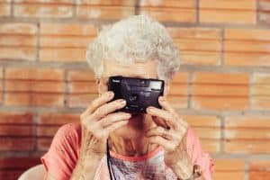 An old woman uses a camera to take a photo