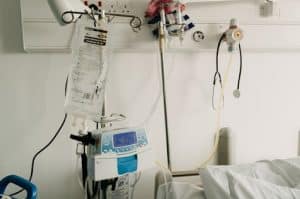 An IV bag for infusion therapy is next to a hospital bed