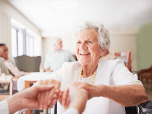 An elderly woman smiling as someone holds her hands