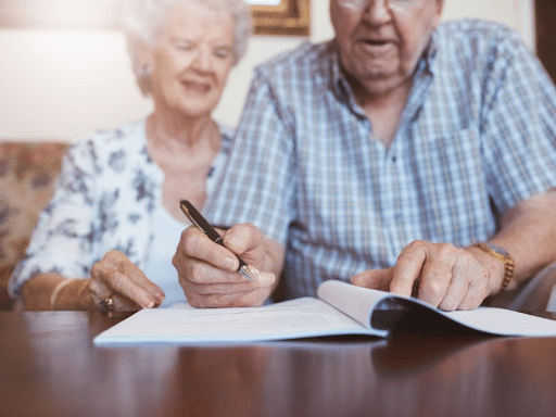 an elderly couple signing documents regarding their estate